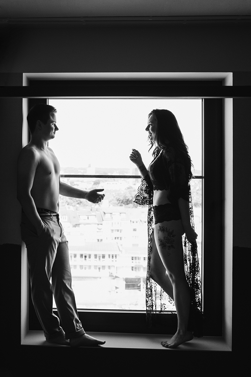 Paar steht in Unterwäsche am Fenster für ein coupleboudoir fotoshooting