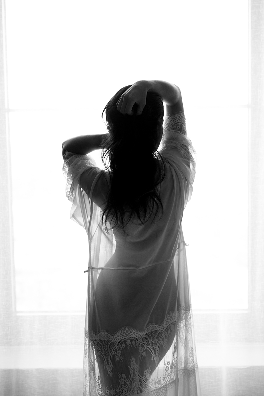 Frau steht in Unterwäsche am Fenster für ein Boudoir fotoshooting