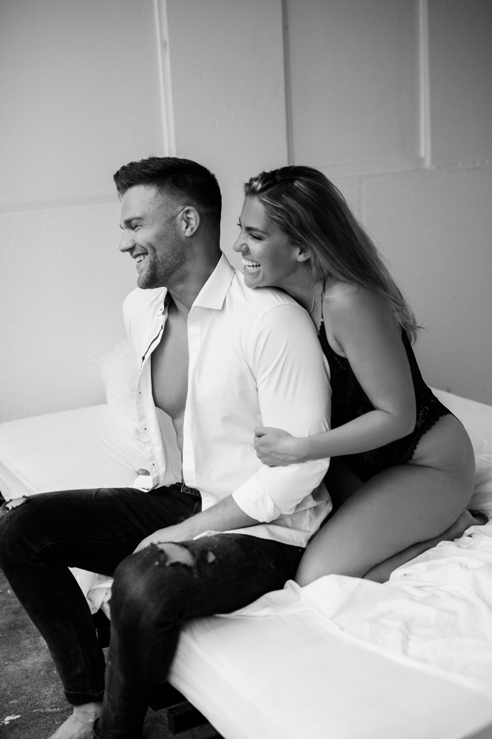Paar sitzt in aufreizender Pose auf einem Bett für ein Couple Boudoir Fotoshooting