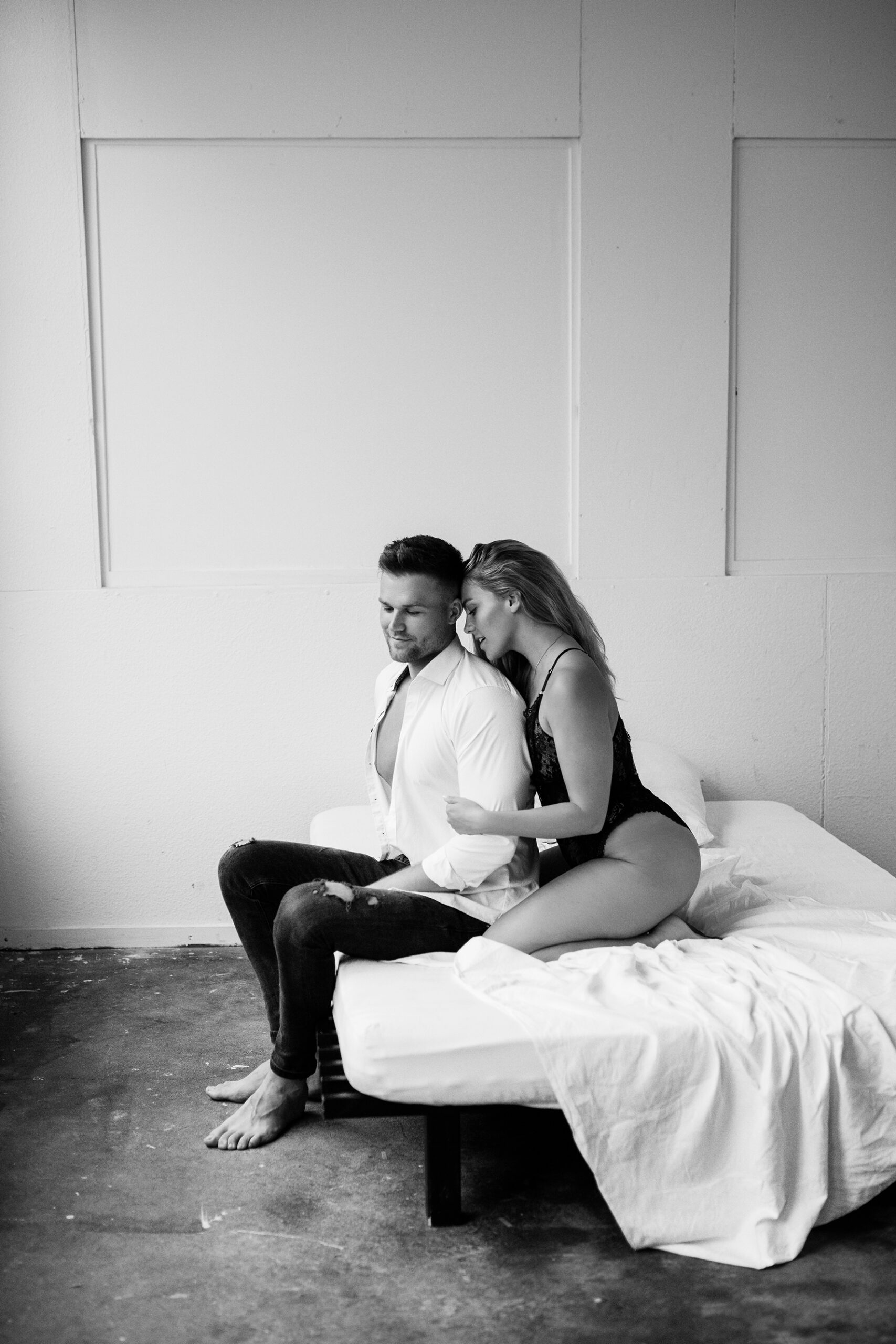 Paar sitzt in aufreizender Pose auf einem Bett für ein Couple Boudoir Fotoshooting