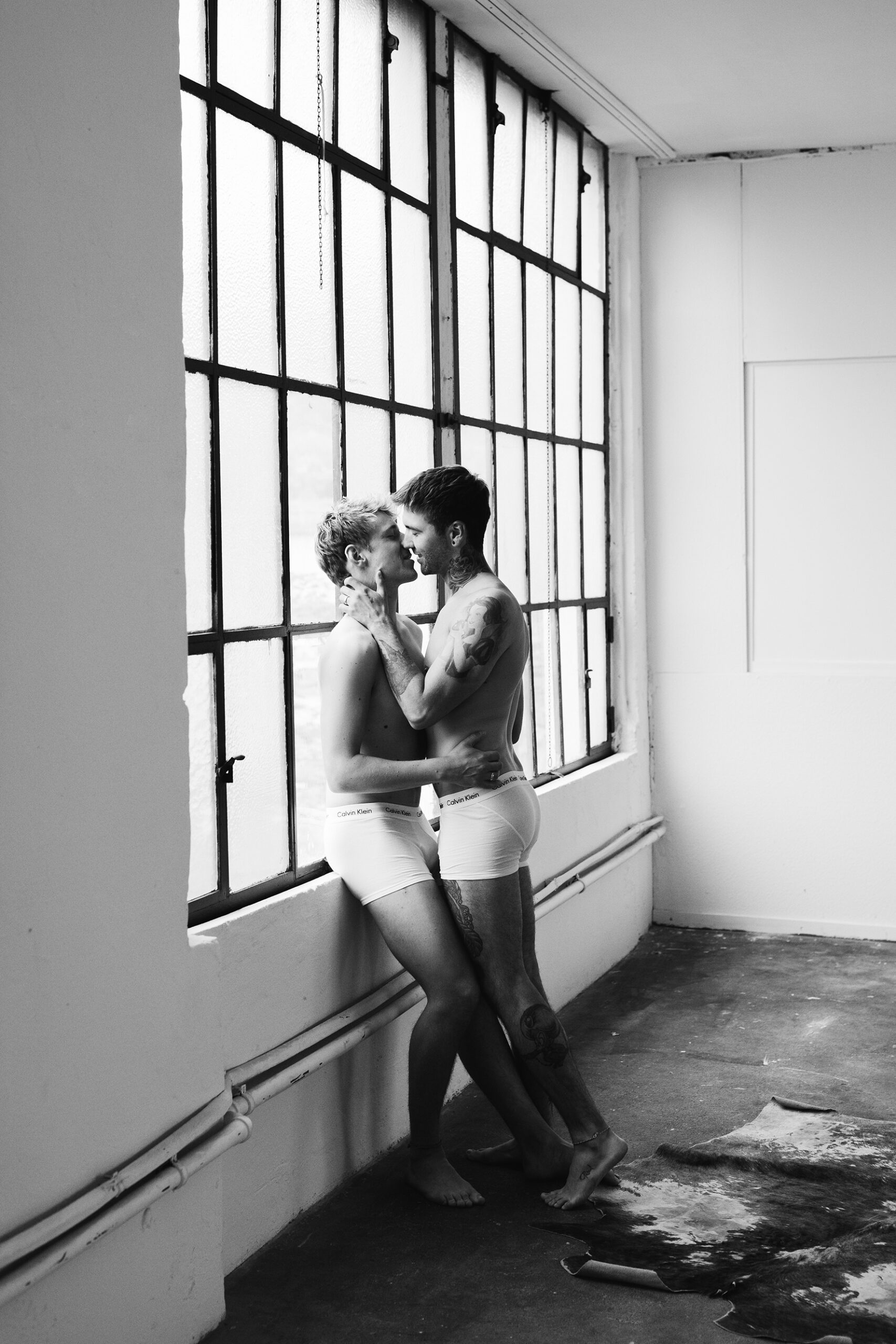 Schwules Paar steht vor Fenstern für Couple Boudoir fotos