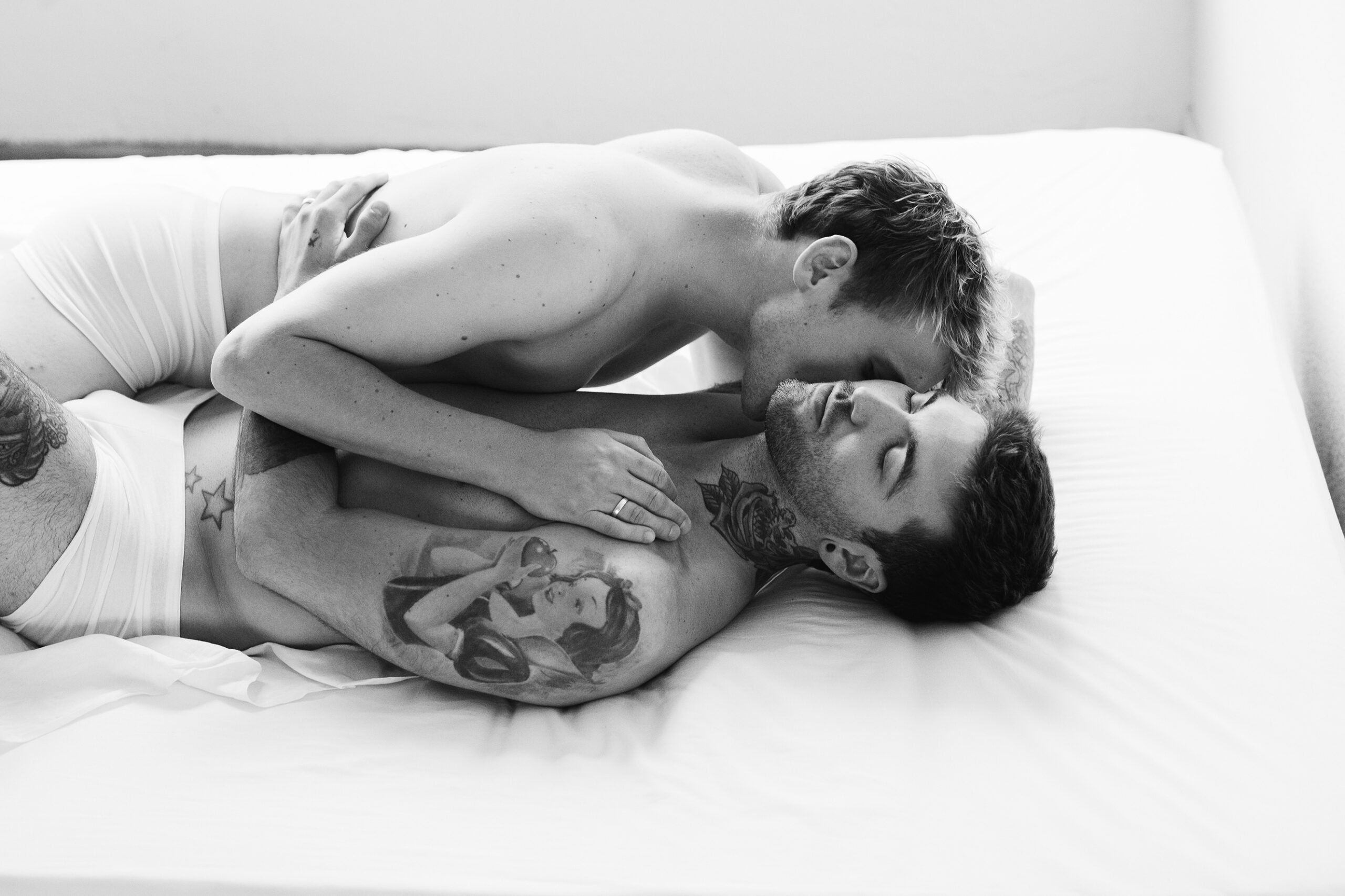 Schwules Paar liegt in Unterhosen auf einem Bett für CoupleBoudoir fotos