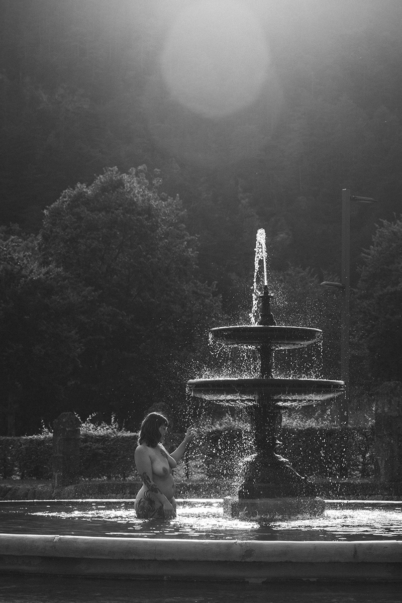 Frau steht nackt in einem Brunnen