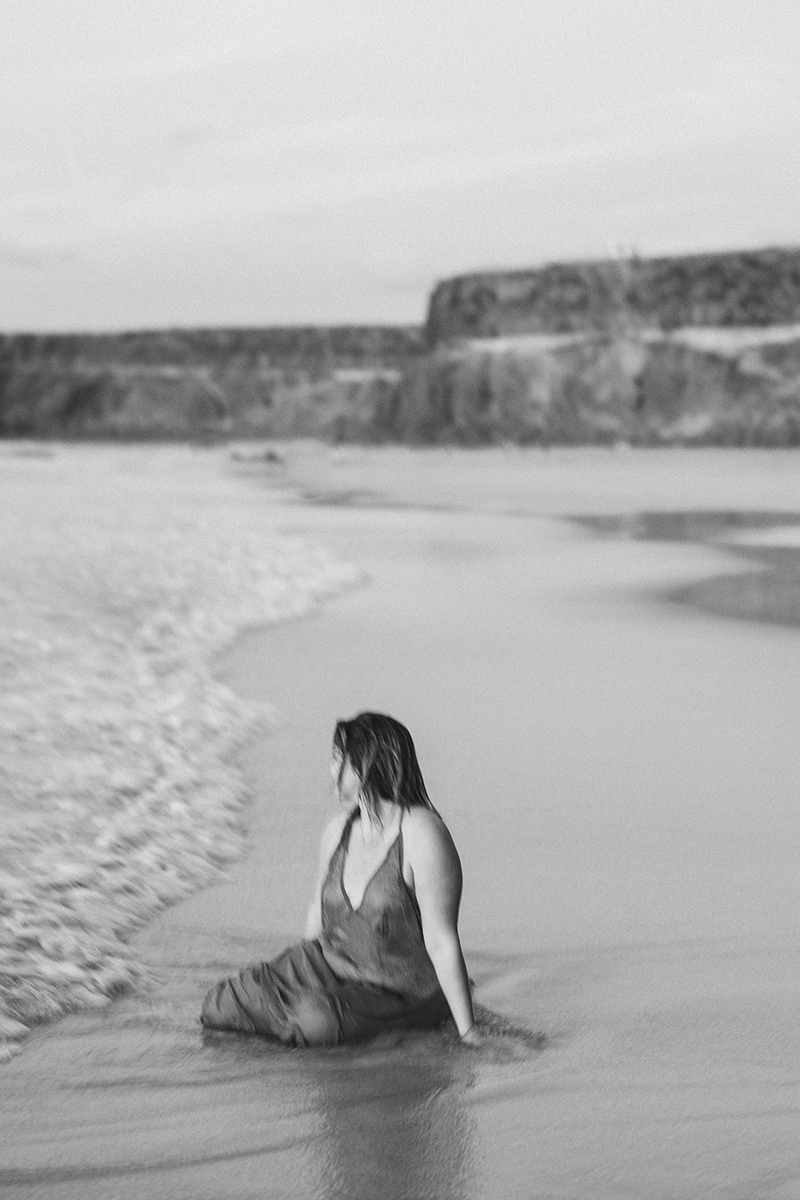 Frau sitzt am strand und ist eins mit der Natur