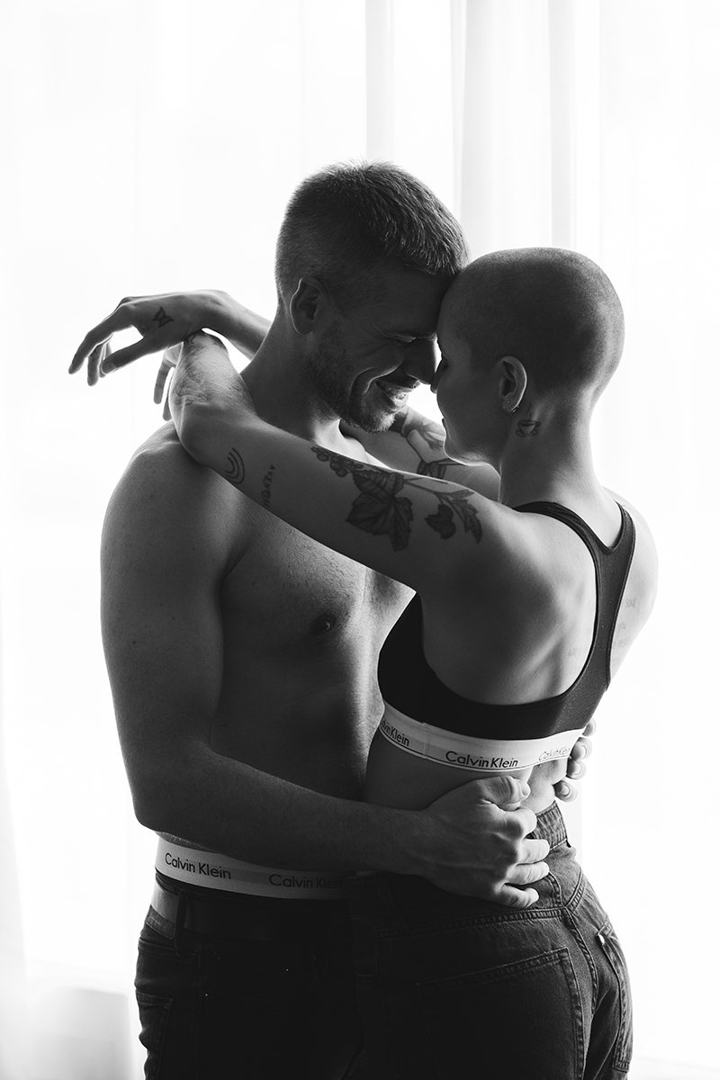 Paar dass sich innig umarmt, vor einem großen Fenster, in Unterwäsche